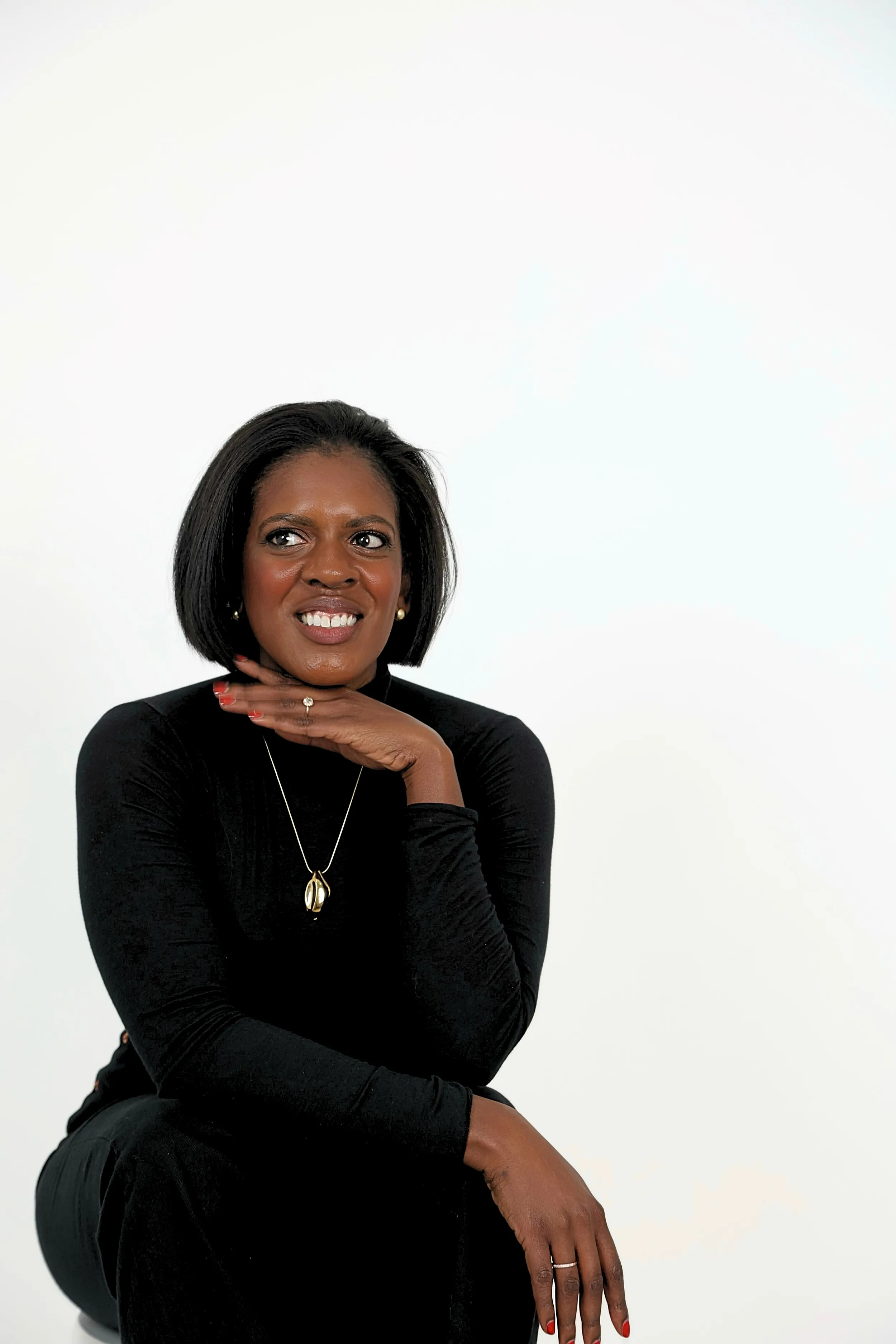 Ashley Rudolph in a black turtleneck, smiling with her chin on her hand.